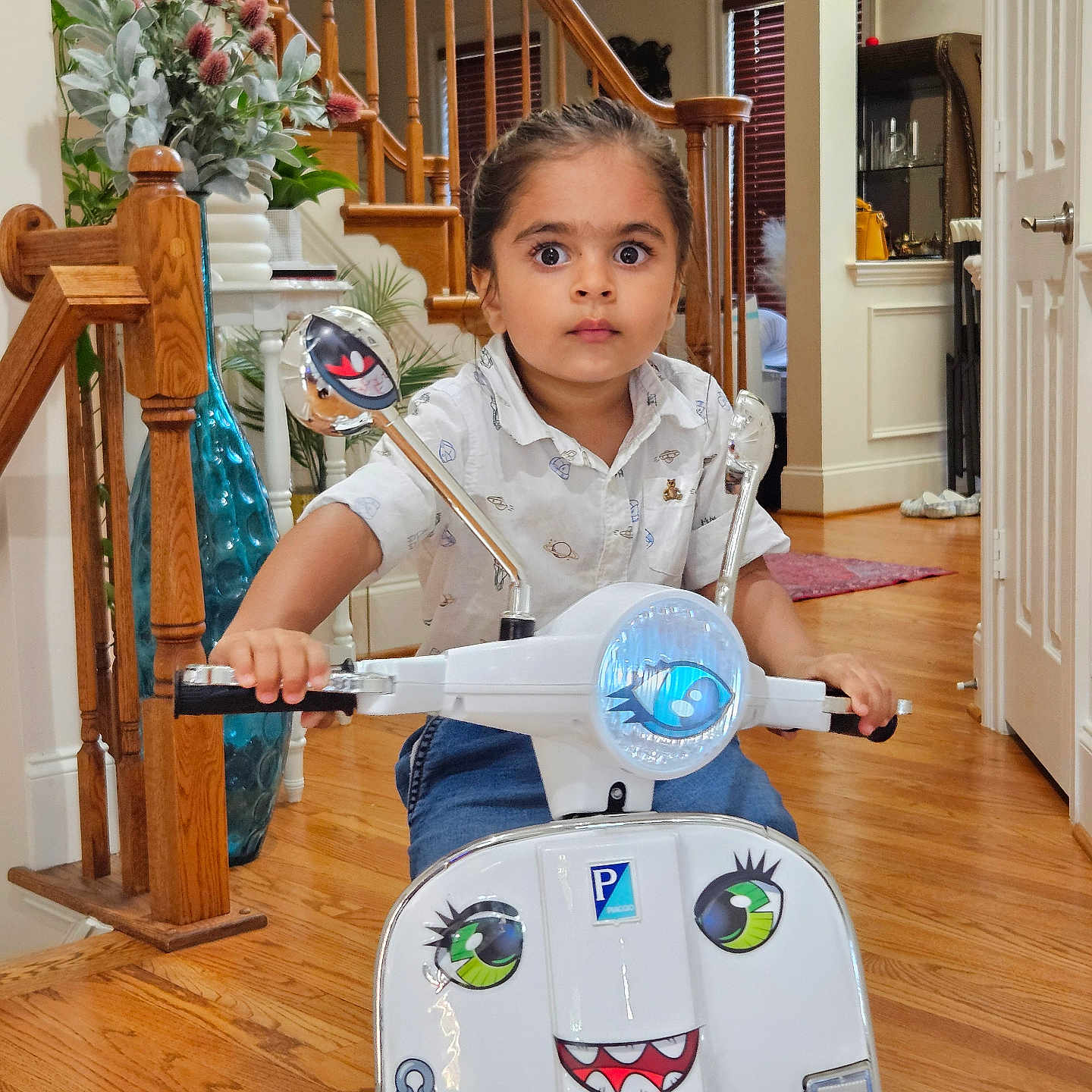 Avyan is registered to the contest to win money with this photo: blue_jeans, child, decor, door, expression, face_sticker, floor, hand, indoor, mirror, plant, playful, staircase, toy_scooter, vase, white_shirt, wide_eyes, window, wooden_floor, young