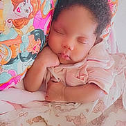 Breanna is registered to the contest to win money with this photo: baby, infant, sleeping, portrait, face, curly_hair, indoors, bed, bedding, blanket, pillow, pink, princess, cartoon, peaceful, resting, hand, onesie, nursery, close_up