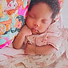 baby, infant, sleeping, portrait, face, curly_hair, indoors, bed, bedding, blanket, pillow, pink, princess, cartoon, peaceful, resting, hand, onesie, nursery, close_up