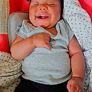 Breanna joined the competition — help win amazing prizes! baby, bed, black_pants, blanket, child, clothing, cozy, face, gray_shirt, hands, happy, indoor, infant, laughing, lying_down, nursery, photograph, pigtails, portrait, smiling