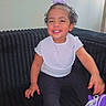 Nexielys joined the competition — help win amazing prizes! toddler, child, smiling, purple_shoes, hair_accessory, white_shirt, black_pants, sitting, couch, indoor, happy, cute, fashion, footwear, person, portrait, young_child, casual, black_background, bright