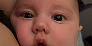 Navy is registered to the contest to win money with this photo: baby, close_up, face, child, infant, skin, cheeks, eyes, mouth, arm, yellow_clothing, striped, indoor, person, candid, expression, human, young, head, snuggling