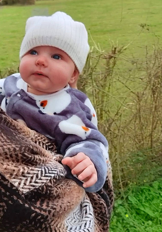 Adam participe au concours pour gagner de l'argent avec cette photo : baby, baby_products, baby_toddler_clothing, beanie, cap, cheek, child, fur, grass, grassland, headwear, outerwear, pattern, people_in_nature, person, plant, sitting, sleeve, terrestrial_animal, toddler