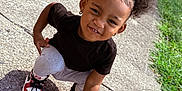 Joliyah joined the competition — help win amazing prizes! child, toddler, smiling, outdoor, sidewalk, hair_clips, butterfly, black_tshirt, gray_pants, sneakers, crouching, sunlight, grass, earrings, curly_hair, happy, playful, person, portrait, casual
