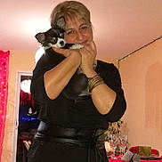 Mambo a rejoint le concours — aidez-le/la à gagner de superbes lots ! black_dog, bracelet, casual_clothing, celebration, curtains, dog, door, evening, glassware, home, hugging, indoor, lights, plant, portrait, red_tablecloth, smiling, table, white_dog, woman