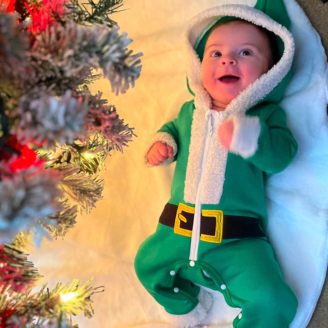Kevin is registered to the contest to win money with this photo: baby, bonnet, cap, christmas, christmasdecorations, clothing, coat, costume, face, festival, glove, hat, head, hood, knitwear, person, photography, plant, portrait, tree
