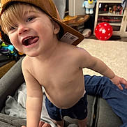 Grayson joined the competition — help win amazing prizes! toddler, child, cap, shirtless, smiling, tongue_out, indoor, living_room, couch, hand, toy, television, carpet, shorts, person, happy, playful, home, furniture, curtain