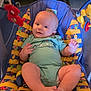 baby, infant, bouncer, toy, onesie, child, seated, playful, colorful, cute, comfortable, indoor, smiling, person, face, legs, feet, hand, fabric, pattern