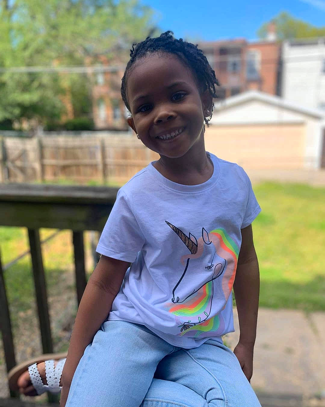 Mazi is registered to the contest to win money with this photo: chin, cool, facial_expression, fun, grass, hair, hairstyle, happy, joy, knee, leisure, person, plant, sleeve, smile, standing, summer, thigh, toddler, tree