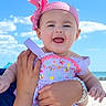 baby, child, smiling, headband, bow, romper, embroidery, hand, bracelet, outdoor, sky, clouds, beach, sunny, portrait, person, happy, infant, summer, vacation