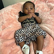 Andrea is registered to the contest to win money with this photo: baby, infant, blanket, pink, clothing, leopard_print, shoes, hands, face, person, cute, lying_down, indoor, wall, fashion, footwear, soft_texture, child, young, portrait