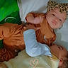 baby, infant, child, bed, pillow, headband, leopard_print, clothing, white, brown, yellow, fuzzy_vest, green_background, heart_doodle, cuddling, sleeping, cute, indoors, soft_texture, portrait