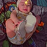 baby, child, infant, playing, bed, blanket, headband, flower, footwear, white_shoes, colorful, smiling, cute, indoors, person, lying_down, happy, face, skin, clothing