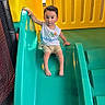 Carinlefty joined the competition — help win amazing prizes! child, toddler, slide, playground, indoor, yellow, teal, plastic, clothing, barefoot, shorts, tank_top, face, curly_hair, handrail, play_area, heart_graphics, sitting, looking, colorful