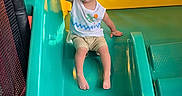 Carinlefty joined the competition — help win amazing prizes! toddler, child, slide, playground, indoor, yellow, turquoise, plastic, play, fun, smiling, clothing, shorts, tank_top, barefoot, heart_graphics, colorful, sitting, handrail, metal_mesh
