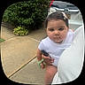 Arya is registered to the contest to win money with this photo: baby, child, person, sidewalk, outdoor, greenery, bush, car, black_car, white_clothing, hair_clip, hand, holding, cute, face, portrait, curious, infant, young_child, nature