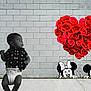 baby, black_and_white, brick_wall, cartoon, child, cute, diaper, flowers, heart_shape, looking_away, love, mickey_mouse, minnie_mouse, outdoor, pacifier, playful, red_roses, sidewalk, toddler, wall_art