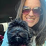 woman, dog, black_dog, smiling, sunglasses, pet, car_interior, collar, fluffy_dog, portrait, happy, casual_clothing, long_hair, indoor, closeup, friendship, companion, cute_pet, sunlight, leisure