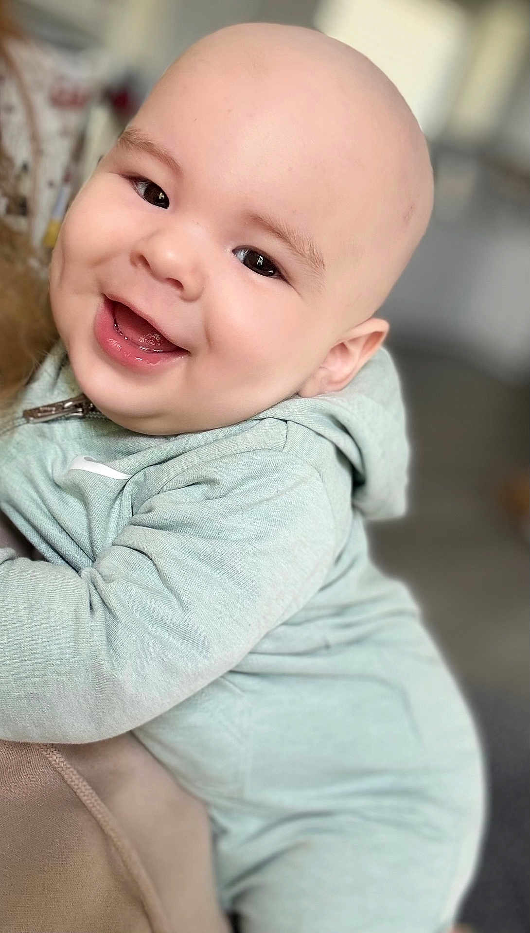 Santiago is registered to the contest to win money with this photo: baby, child, smiling, hoodie, bald, face, person, clothing, happy, cute, infant, portrait, closeup, expression, sitting, indoor, skin, young, warm, comfort