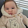 baby, child, coat, jacket, hood, face, smile, indoors, window, blinds, cute, warm_clothing, portrait, infant, soft_light, person, apparel, button, expression, fur_trim