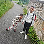 child, children, boy, young_child, school_child, backpack, hoodie, sneakers, pavement, stone_wall, metal_fence, greenery, pathway, outdoor, posing, playful, serious, sidewalk, casual_clothing, urban