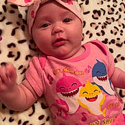 Ariella is registered to the contest to win money with this photo: baby, infant, pink_clothing, headband, blanket, leopard_print, baby_shark, cute, smiling, lying_down, child, portrait, indoor, happy, toddler, colorful, apparel, face, person, cozy