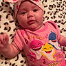 baby, infant, pink_clothing, headband, blanket, leopard_print, baby_shark, cute, smiling, lying_down, child, portrait, indoor, happy, toddler, colorful, apparel, face, person, cozy