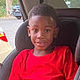 boy, car_interior, car_seat, casual, child, daylight, face, haircut, happy, indoors, parking_lot, people, portrait, red_shirt, seatbelt, sitting, smiling, vehicle, window, young