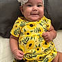 baby, child, smile, happy, dress, yellow, sunflower, headband, flower, infant, cute, portrait, sitting, furniture, quilt, fabric, clothing, skin, person, indoors