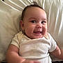 Jaelynn is registered to the contest to win money with this photo: baby, bed, casual_clothing, child, chubby_cheeks, closeup, cute, expression, face, happy, indoors, infant, lying_down, person, pillow, portrait, skin, smiling, white_onesie, young_child
