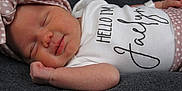 Jaelynn is registered to the contest to win money with this photo: baby, newborn, sleeping, infant, headband, polka_dot, clothing, onesie, text_on_clothing, blanket, soft_texture, cute, peaceful, face, skin, hand, lying_down, portrait, child, resting