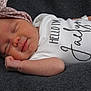 baby, newborn, sleeping, infant, headband, polka_dot, clothing, onesie, text_on_clothing, blanket, soft_texture, cute, peaceful, face, skin, hand, lying_down, portrait, child, resting