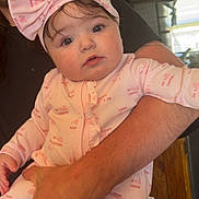 Wrenley joined the competition — help win amazing prizes! baby, child, infant, pink_outfit, headband, bow, adult_arm, kitchen, wooden_cabinets, indoor, portrait, cute, wide_eyes, holding, love_messages, clothing, person, face, expression, home