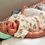 Areliana joined the competition — help win amazing prizes! baby, infant, smiling, headband, bow, onesie, minnie_mouse, patterned_clothing, blanket, bed, happy, cute, tongue_out, lying_down, soft_texture, indoor, child, person, playful, adorable