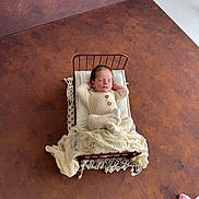 Alfie joined the competition — help win amazing prizes! newborn, baby, infant, sleeping, bed, blanket, knitwear, cozy, resting, portrait, soft, tiny_bed, brown_background, floor, hands_behind_head, peaceful, indoors, warm, cute, pink_sock