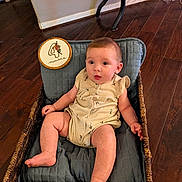 Harper is registered to the contest to win money with this photo: baby, infant, basket, cushion, wood_floor, indoor, child, cute, sitting, clothing, flooring, home, person, face, skin, legs, hands, expression, furniture, soft