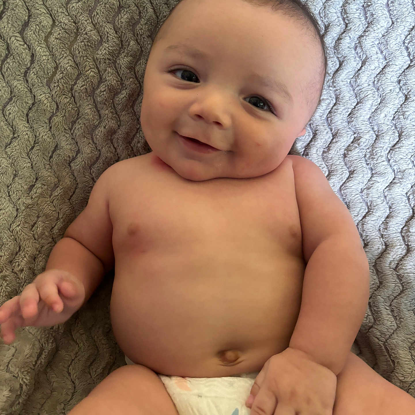 Amoni is registered to the contest to win money with this photo: baby, infant, diaper, smiling, cute, chubby, face, skin, hand, bare_chest, lying_down, texture, blanket, stars, expression, portrait, child, happy, young, baby_boy