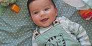 Telio participe au concours pour gagner de l'argent avec cette photo : baby, child, childcare, clothing, cute, expression, face, happy, indoor, infant, lying_down, overalls, patterned_mat, person, playmat, portrait, smiling, soft_toys, striped_shirt, toy