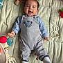 baby, child, smiling, striped_overalls, blue_shirt, sock, giraffe_toy, rattle, soft_quilt, toy, infant, cute, happy, lying_down, playtime, indoors, person, face, small_child, colorful