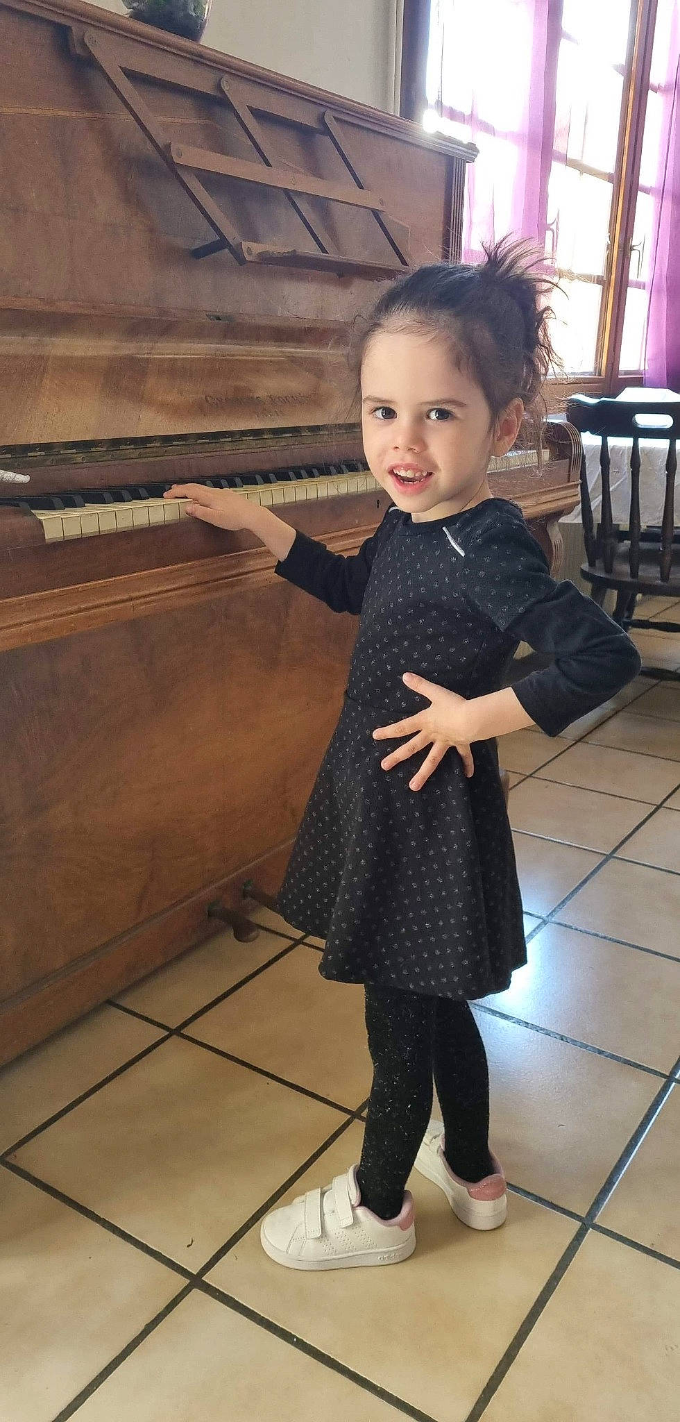 Lena participe au concours pour gagner de l'argent avec cette photo : chair, dress, fashion_design, flash_photography, floor, flooring, formal_wear, hairstyle, happy, joint, leg, musical_instrument, one_piece_garment, person, piano, shoulder, skin, sleeve, smile, toddler