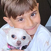 Skye is registered to the contest to win money with this photo: boy, child, dog, pet, white_dog, smiling, hugging, close_up, collar, indoor, cute, young, portrait, affection, friendship, happy, human_animal_bond, casual_clothing, short_hair, brown_eyes