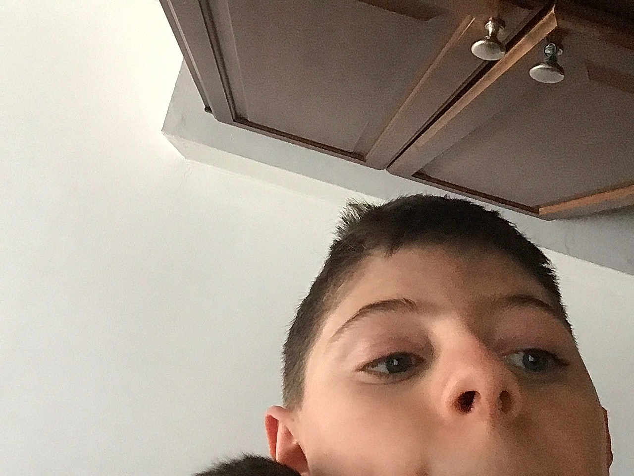 Fluffy is registered to the contest to win money with this photo: child, boy, face, selfie, indoor, ceiling, cabinet, wood, hair, skin, nose, ear, eye, portrait, casual, young, closeup, expression, background, lighting