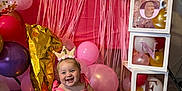 Hadlie is registered to the contest to win money with this photo: baby, birthday, pink_dress, crown, balloon, carpet, smiling, decorations, gold_balloon, number_one, stacked_boxes, party, celebration, indoor, happy, child, festive, colorful, toddler, cute