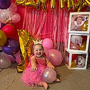 Hadlie joined the competition — help win amazing prizes! baby, child, birthday, party, pink_dress, crown, balloon, gold_balloon, number_one, blocks, carpet, smiling, celebration, indoors, decorations, happy, cute, one_year_old, festive, playful