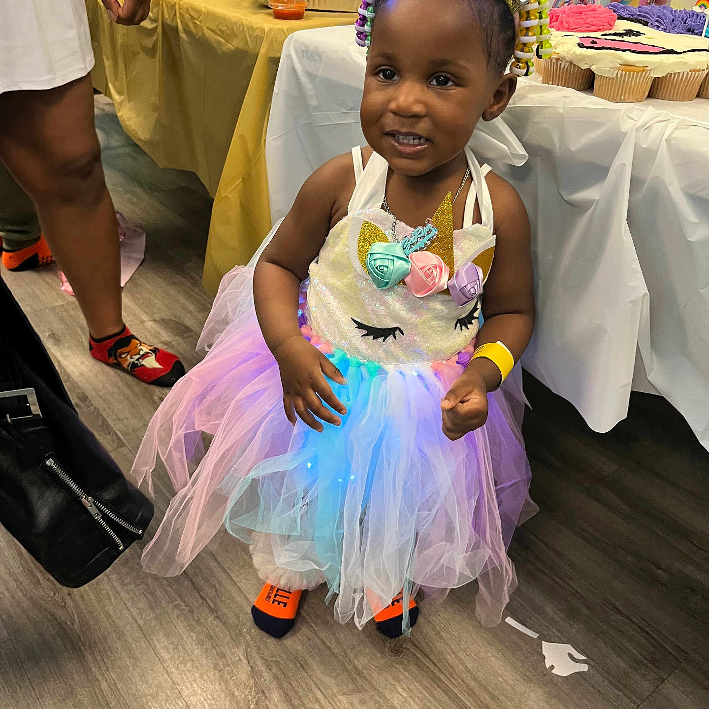 Zarya joined the competition — help win amazing prizes! celebration, child, colorful, cupcakes, decoration, dress, floor, food, hand, happy, headband, indoor, light, party, person, smiling, socks, table, toddler, unicorn_costume