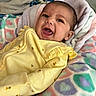 Romy is registered to the contest to win money with this photo: baby, bee_pattern, blanket, child, colorful_blanket, cozy, cute, funny_face, happy, head, heart_pattern, indoors, infant, lying_down, person, portrait, smile, soft_texture, yellow_clothing, young_child
