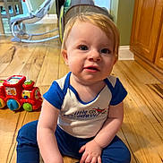 Lincoln is registered to the contest to win money with this photo: toddler, child, baby, floor, toy, red_train, blue_clothing, wooden_floor, indoor, home, cabinets, curious, sitting, playtime, cute, smiling, person, young_child, hands, face