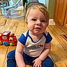 toddler, child, baby, floor, toy, red_train, blue_clothing, wooden_floor, indoor, home, cabinets, curious, sitting, playtime, cute, smiling, person, young_child, hands, face