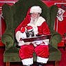Hennessy joined the competition — help win amazing prizes! santa_claus, cat, armchair, christmas, holiday, red_clothing, white_beard, hat, boots, glasses, decorations, stockings, plants, red_background, green_furniture, festive, indoor, pet, reading, cozy