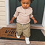 Luca joined the competition — help win amazing prizes! toddler, child, afro_hair, standing, door, porch, doormat, wooden_floor, green_door, casual_clothing, white_sneakers, looking_down, outdoor, front_door, home, young_child, curly_hair, long_sleeve_shirt, pants, footwear